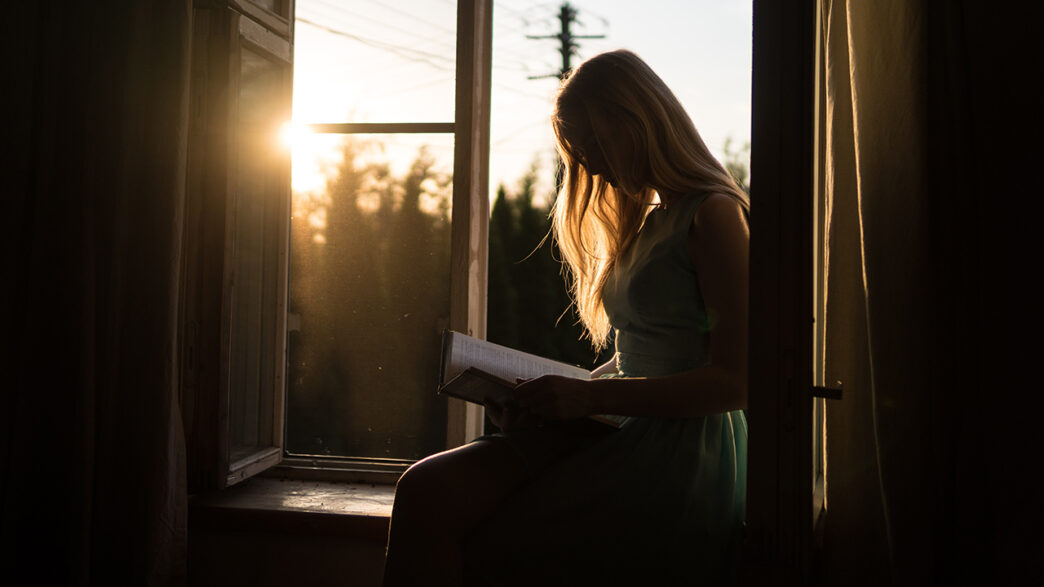 窓辺で本を読む女性